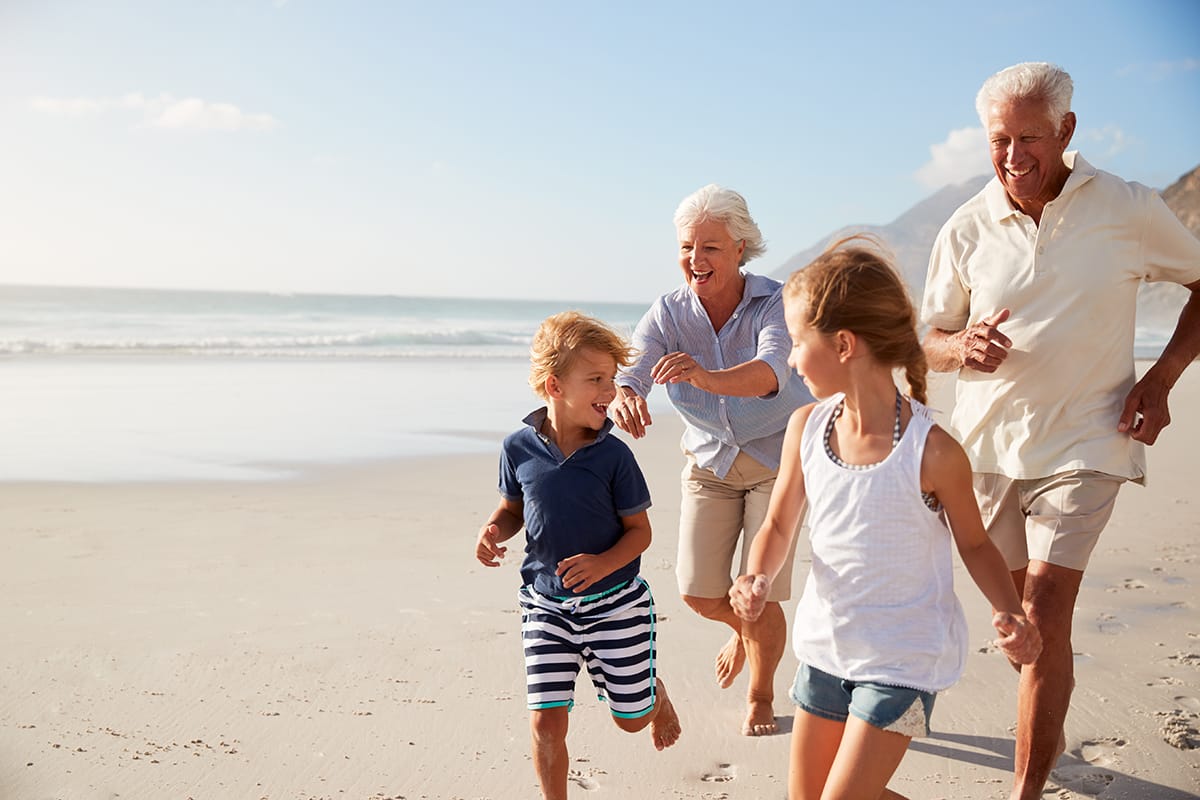 Grandparents Running Along Beach With Grandchildren On Summer Va Grandparents Running Along Beach With Grandchildren On Summer Vacation